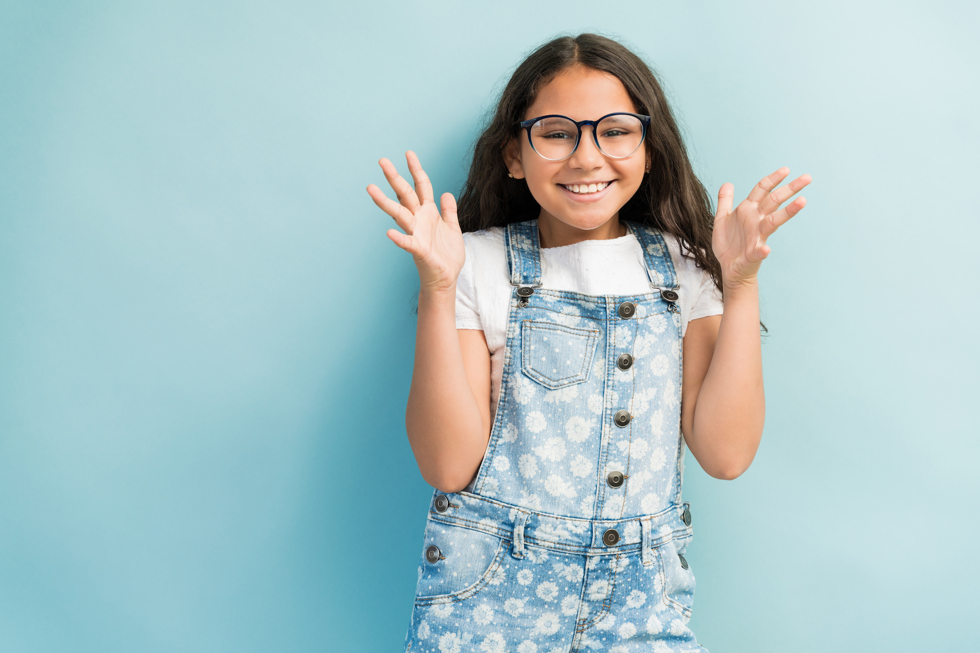 Cheerful Latin girl gesturing while making eye contact isolated against plain background